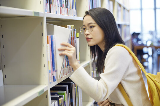 Student browsing books on library shelves