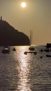 Golden sunset over Port de Soller, Mallorca, with sailboats and yachts silhouetted on calm Mediterranean waters, creating a peaceful coastal evening atmosphere.