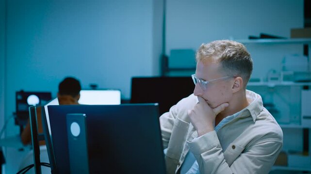 Young male software developer typing and thinking of code system while designing website and AI software on computer in tech office