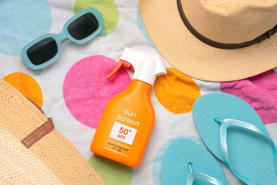Top view of bottle of sunscreen with 50+ written on it,sunglasses and beach items. Concept of sun protection