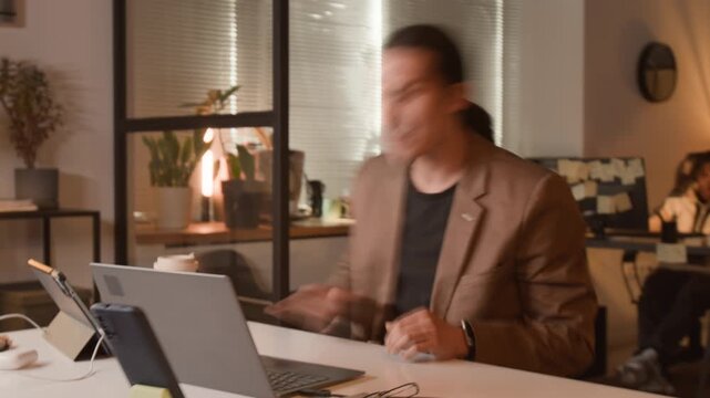 Young Asian programmer typing on laptop in fast motion during late night office hours, celebrating success. Clip for software development and IT startup commercial campaigns