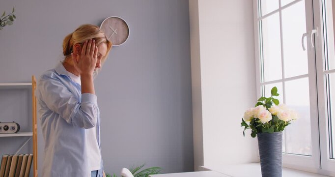 Young female feeling unwell at home, dizziness or migraine, touching head, weak and dizzy, losing consciousness at home, sudden headache, spinning around and losing balance, unsteady moving 