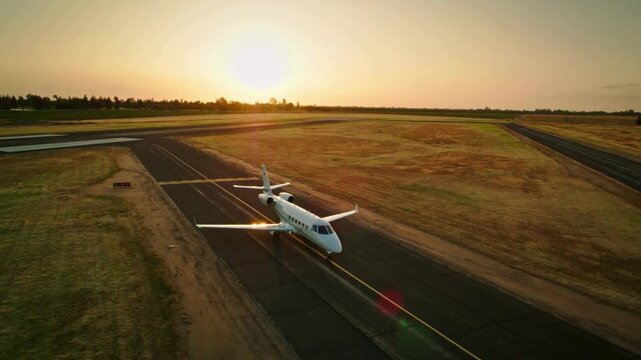 Private business jet airplane taxiing on an airport runway at sunset