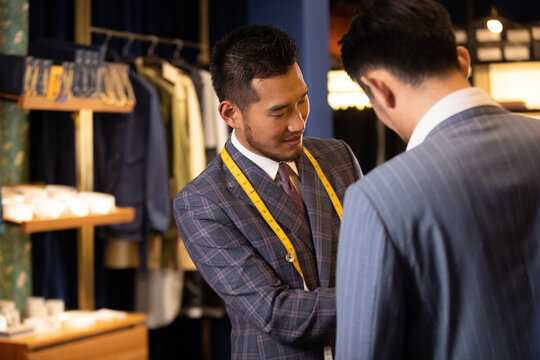 Tailor measuring customer for custom suit fitting in menswear shop