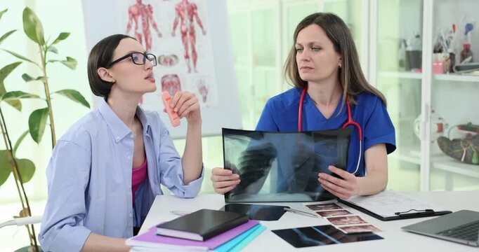 Carefree woman vapes as angry doctor shows lungs x-ray image in clinic. Physician attracts attention to negative impact of smoking on health