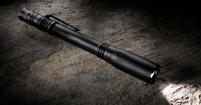 Small penlight flashlight on a large boulder