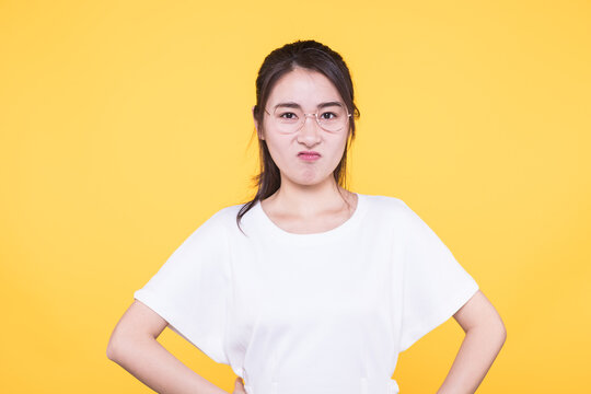 Young woman with glasses making a displeased face on yellow background