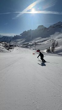 A skier carving down perfectly groomed slopes in Dolomiti Superski. Endless alpine views, fresh snow and sunny winter days in the heart of the Italian Dolomites