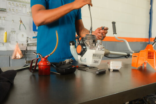 Technician performing maintenance on grass trimmer engine