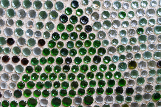 Decorative wall constructed from recycled glass bottles inside a bottle house in Prince Edward Island Canada featuring intricate geometric patterns created from green clear and coloured glass