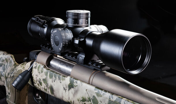 Large scope on a bolt action rifle with a dark background