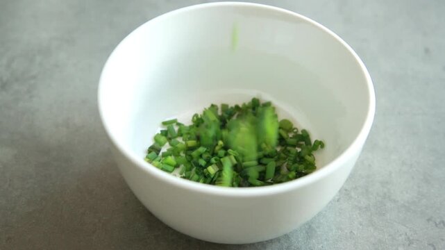 Close-up of a finely chop fresh green chives on a clean white cutting board