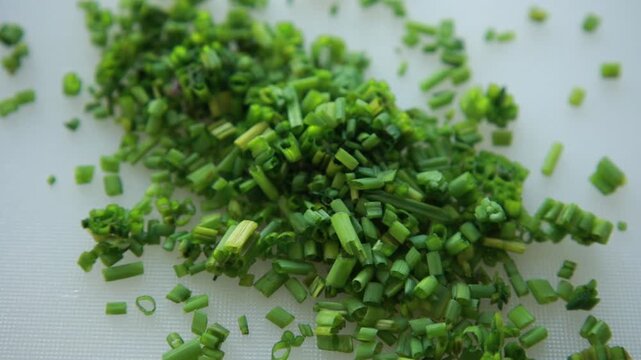 Close-up of a finely chop fresh green chives on a clean white cutting board