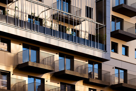 Warm sun cuts across dark balcony lines on a residential apartment facade in Nordbahnviertel, Vienna, Austria, revealing urban architecture, windows, and shadow