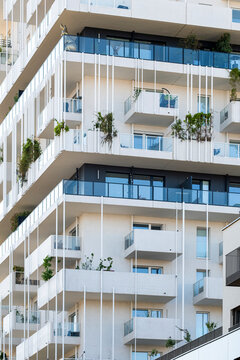White balcony rows and plants define a residential apartment building facade in Nordbahnviertel, Vienna, Austria, where urban architecture catches daylight