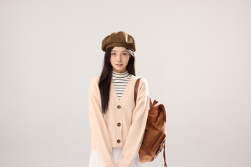 Fototapeta premium Stylish young woman in beret with backpack on neutral studio background
