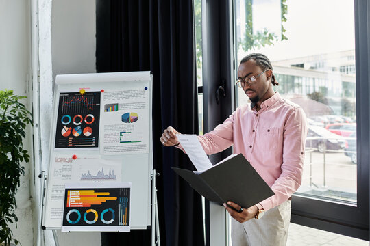 Young man presenting innovative ideas in a modern workspace with charts and data