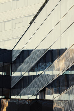 Angled facade lines cross glass windows on an urban building, where vertical architecture, reflection, shadow, and geometry create a sharp exterior pattern