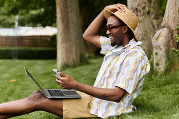 Young African American man enjoying remote work in a sunny outdoor setting © LIGHTFIELD STUDIOS
