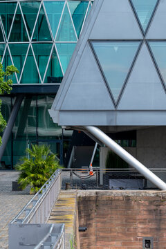 Triangular pattern, glass facade, and stair railings shape a modern urban building entrance with reflection, structure, and exterior light