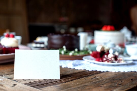 Blank card on rustic table with cakes and desserts in a cozy setting