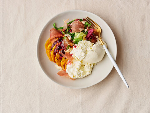 Seasonal roasted squash salad with creamy burrata and prosciutto, gourmet restaurant menu, upscale dining experience