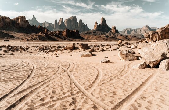 Stunning Desert Landscape with Tire Tracks in the Sand and Jagged Mountain Peaks in the Sahara Desert