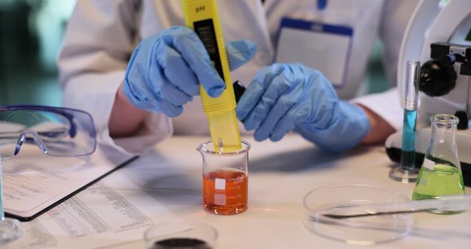 Female technician analyzes liquid pH with digital meter in chemical lab. Assistant uses precise tool to research fluid in laboratory slow motion