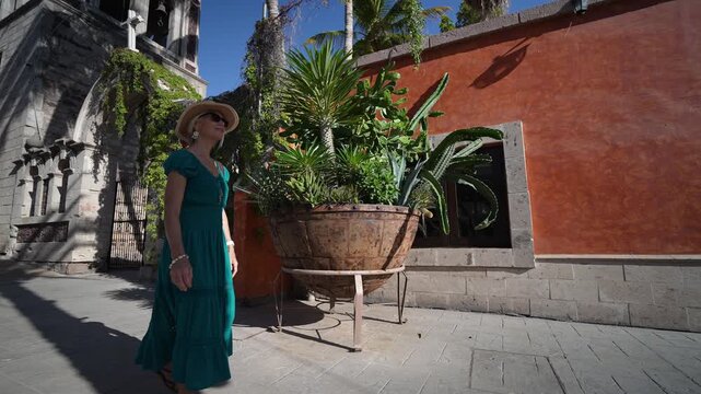 Mature woman enjoys her adventure walking near Loreto mission church, taking in the sights and feeling excited about her journey.