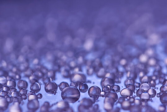 Macro photography of purple water droplets on a reflective surface