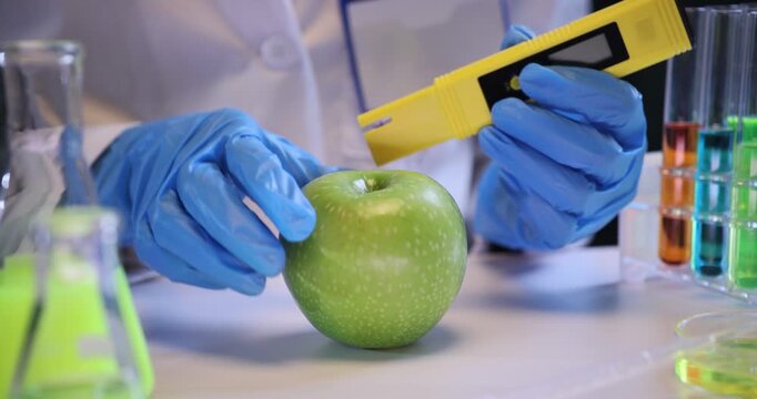 Scientist uses pesticide residue meter to check apple in laboratory. Assistant tests fresh fruit for nitrates contamination in workplace slow motion