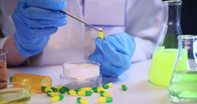 Pharmacist hands fill capsule with white powder at desk in lab. Medical worker makes experimental drugs for disease treatment in hospital slow motion