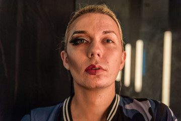 Person with makeup on one side of face, standing in dim lighting. © Rawpixel.com