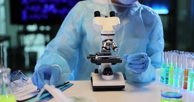 Experienced researcher places drop of transparent liquid with pipet onto microscope slide. Laboratory worker examines sample under powerful microscope