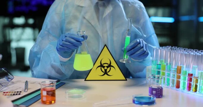Diligent lab worker studies vivid chemical liquids in glass test tubes. Radioactive hazard warning sign stands visibly on table with glassware