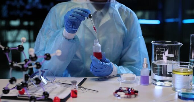 Lab worker analyzes texture and deep bright red color of liquid in glass bottle. Diligent laboratory technician studies reagent samples slow motion
