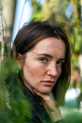 Obraz premium Woman with freckles and brown hair in a natural outdoor setting.