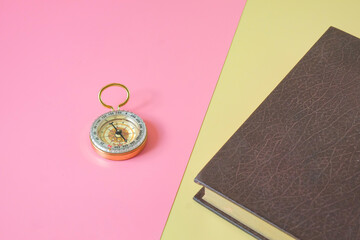 Vintage compass with a heard cover book on two tone background. © amnarj2006