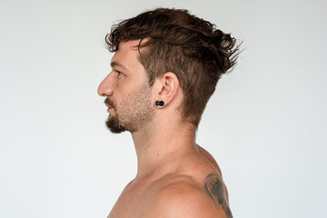 Naklejka premium Profile of a man with curly hair and earrings against a plain background.
