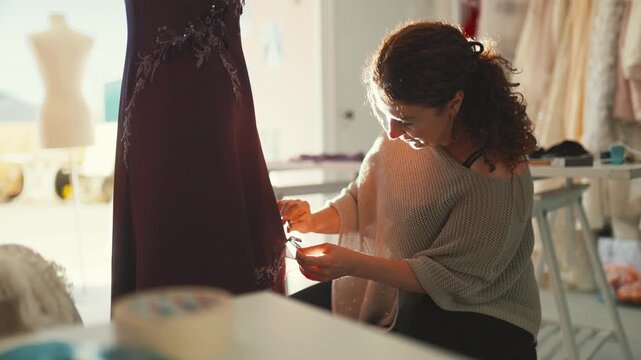 Woman sewing a dress in a bright workshop during the afternoon