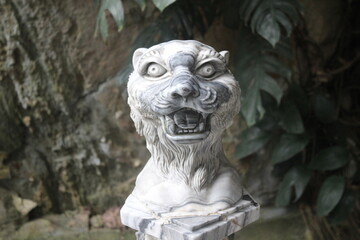 Obraz premium Ferocious tiger head sculpture carved from white marble on a stone base platform.