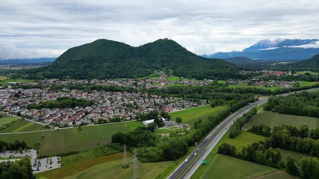 A scenic aerial drone view looking over the Brod district in Ljubljana, Slovenia, with the prominent double-peaked Smarna Gora hill rising in the mid-ground. Patchwork allotment gardens and fields