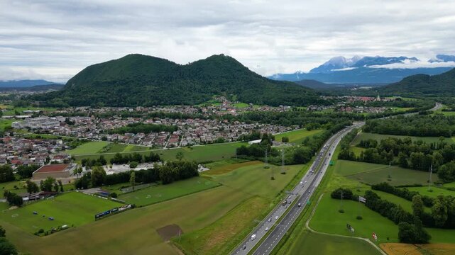 A scenic aerial drone view looking over the Brod district in Ljubljana, Slovenia, with the prominent double-peaked Smarna Gora hill rising in the mid-ground. Patchwork allotment gardens and fields