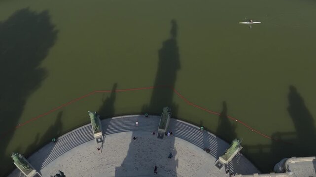 Top down aerial shot of Alfonso XII statue casting shadow on water