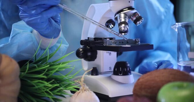 Laboratory worker applies transparent liquid onto clean microscope slide. Scientific worker examines sample through modern scientific microscope