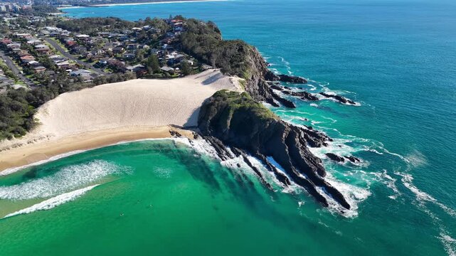 Aerial video panning around Bennetts Headland and the prominent sand dune at One Mile Beach near Forster, NSW, Australia