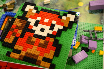 Naklejka premium A Lego bear on a board against a background of multi-colored Lego bricks. Poland. Warsaw.