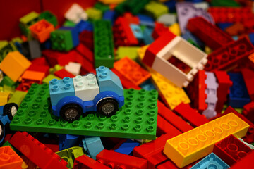 Naklejka premium A Lego car against a background of multi-colored Lego bricks. 