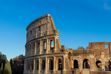 Obraz premium Famous Coliseum in Rome. Colosseum, or Coliseum. Sunset at huge Roman amphitheatre, Rome, Italy, Europe. Famous touristic place in the world and Europe. Beautiful blue sky background.