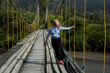 Fototapeta premium Woman walking on rustic suspension bridge enjoying nature